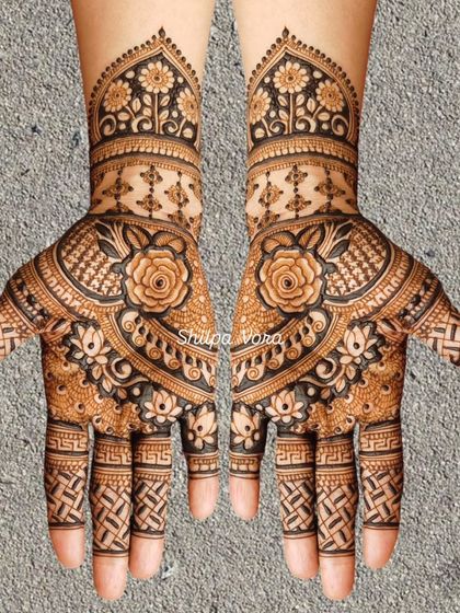 A symmetrical floral design with a large rose as the central element, surrounded by intricate patterns.