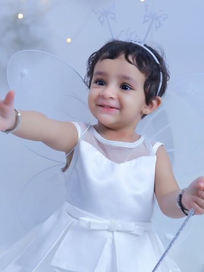 A happy little fairy reaching out with a welcoming smile. The all-white outfit and background create a pure and magical feel for this portrait.