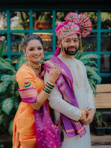 A lovely portrait of the bride resting her hand on the groom's shoulder, both looking confidently at the camera, showcasing their wedding day look.