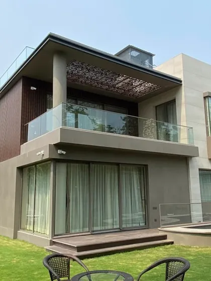 The completed villa in Gurgaon, viewed from the garden. This photo shows the final structure, including the large sliding glass doors and the perforated pergola on the upper terrace, all built according to our 3D models like image 14 and 16.