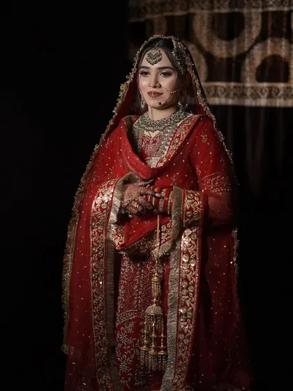A full-length professional shot against a dark backdrop, making the red of her lehenga pop. The makeup is classic and timeless.