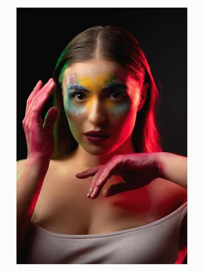 Another pose from the colored powder shoot, showing the model's hands framing her face.