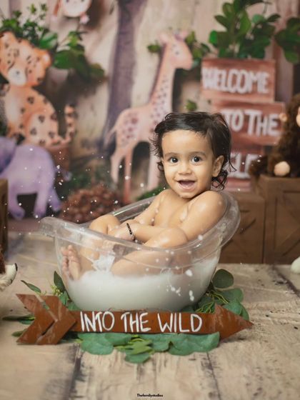 A full view of the jungle-themed milk bath, showing the baby happily sitting in the tub surrounded by props.