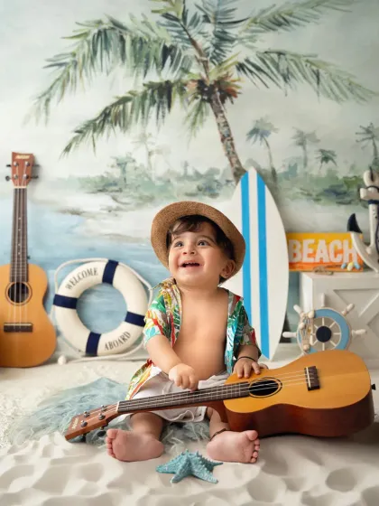 A little musician in the making! A toddler plays with a ukulele during his fun, tropical-themed baby photoshoot.
