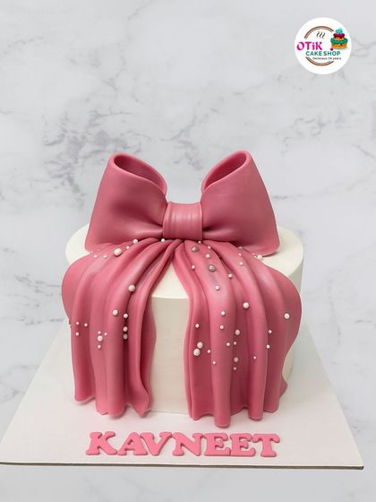 This cake is all about making a statement with a bold pink fondant drape and bow. The pearl-like sprinkles add a touch of glamour, making it perfect for a fashion-forward celebration.