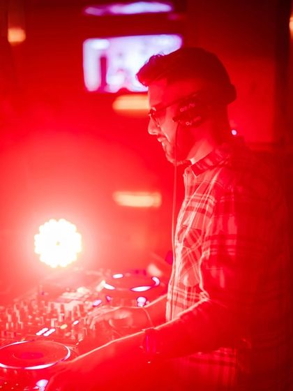 A smiling shot while mixing, bathed in red light.