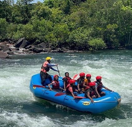 A wide shot of a raft navigating the rapids, with the instructor steering from the back.