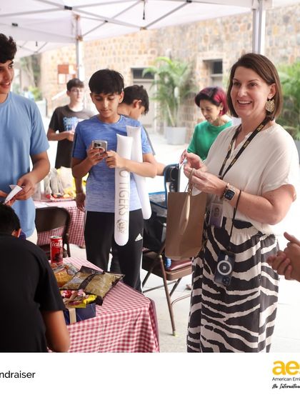 A teacher supports a student-led fundraiser, purchasing items and encouraging their efforts. The entire community gets behind these initiatives, reinforcing our school's commitment to service.