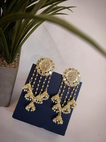 A product shot of the Eid special golden pearl jhumka earrings, resting elegantly on a presentation box.