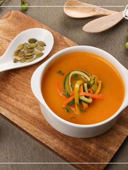 A warm bowl of our vegetable soup, garnished with zucchini ribbons and pumpkin seeds. It's a perfect light meal, packed with vitamins and flavor to nourish your body.