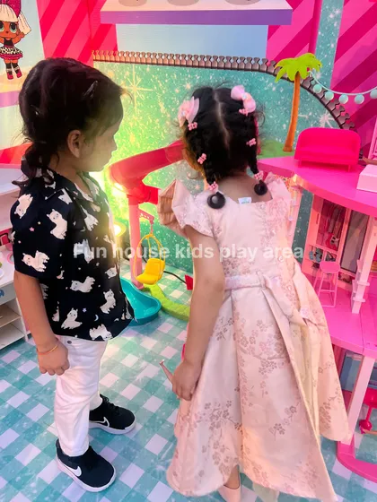 Two children interacting in the pretend play area, highlighting the social aspect of imaginative games.