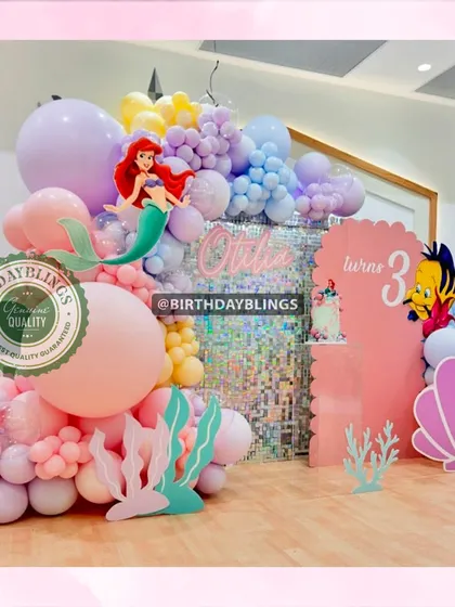 A vibrant Little Mermaid party with a pink shimmer wall and pastel balloon arrangements. Ariel, Flounder, and a large seashell cutout create a fun and immersive underwater world.