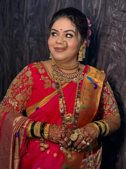 A close-up portrait of the bride, showing her soft makeup and traditional nath.