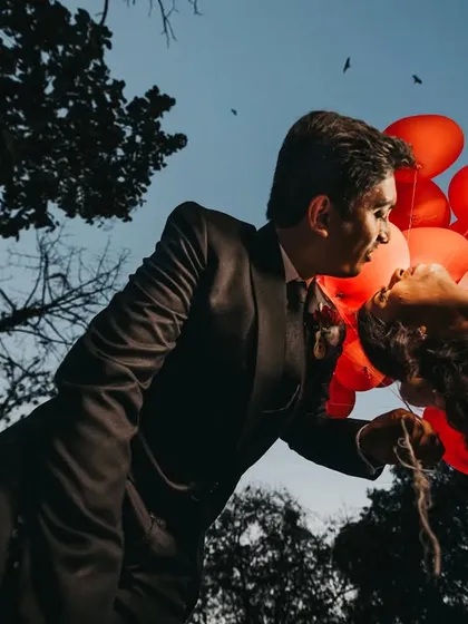 A creative low-angle shot using red heart-shaped balloons to frame the couple. I often lie on the ground to find these unique perspectives that turn a simple prop into a powerful visual element.