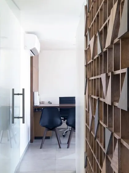 A view from the corridor into one of the consultation rooms. The glass partition allows light to flow through the space, while the wooden screen on the right adds warmth and texture.