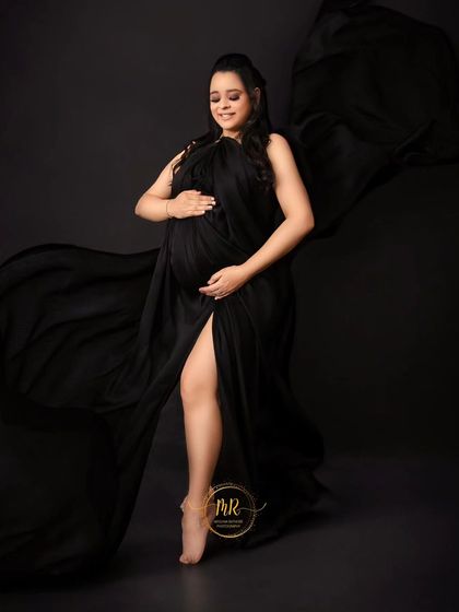 A graceful and artistic pose with flowing black fabric. The mother-to-be is captured mid-motion, creating a sense of dance and freedom in this stunning portrait.