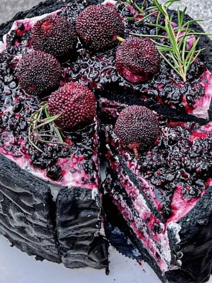 A unique and dramatic take on a classic cake. This black-crusted cake is filled with layers of cream and dark berries, offering a visually striking dessert option for any modern celebration.