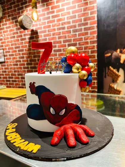 Your friendly neighborhood Spider-Man, ready to swing into your party. This custom cake features a hand-painted, edible image of the superhero, with a 3D fondant hand that looks like it's coming right out of the cake.
