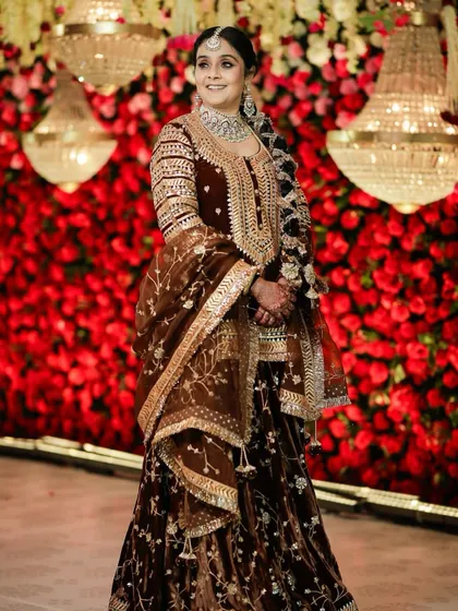 This client is the picture of royalty for her wedding celebration. The makeup was designed to complement her rich, brown velvet outfit, with a focus on defined eyes and radiant skin that glows against the grand floral backdrop.