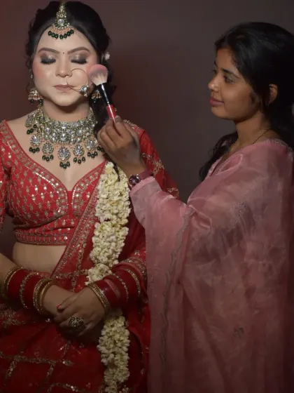 Another student gets hands-on experience creating a classic red bridal look. Notice her focus as she applies blush, a crucial step in balancing a bold lip and heavy eye makeup.