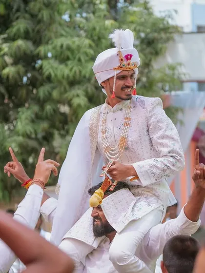 The groom's energetic entry to the wedding venue, carried on the shoulders of his friends and family.