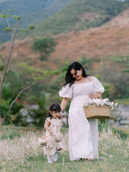A mother and daughter walking in a field, holding a basket of flowers. A poetic and beautiful image.