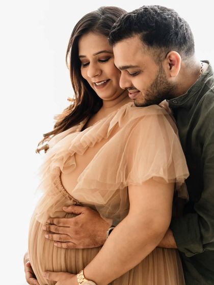 It's all in the details. This close-up shot focuses on their gentle embrace and the soft fabric of her gown, capturing the intimacy and anticipation of waiting for their little one.