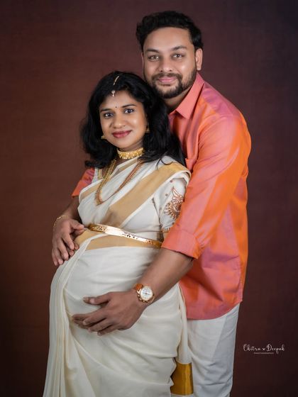 A beautiful portrait of a couple in matching tones. Her elegant white and gold saree is perfectly complemented by his attire.