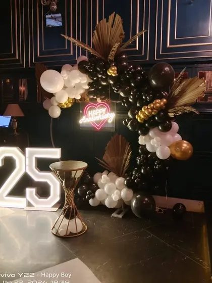 This angle of the 25th anniversary decor shows the elegant combination of the black and gold balloons with the dark, moody interior of the venue.