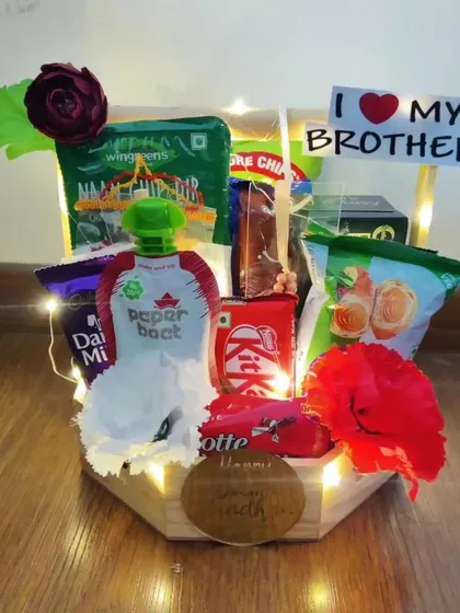 This charming Rakhi basket is lit with warm fairy lights for an extra festive feel. It's filled with snacks, a Paper Boat drink, and chocolates, and decorated with artificial flowers and an 'I Love My Brother' sign.