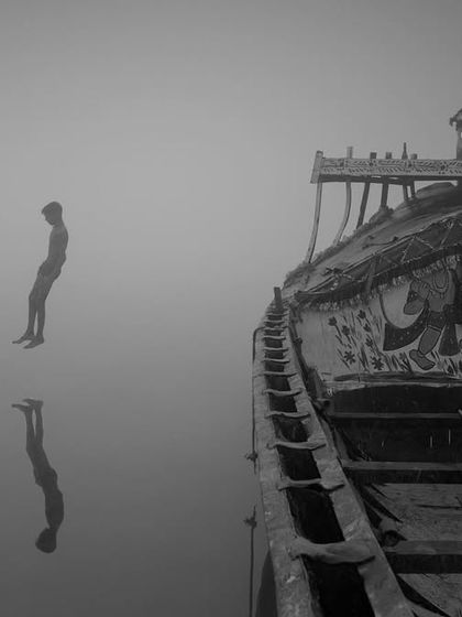 A boy seems to float in the air as he jumps into the water on a foggy morning in Bihar. This black and white photo, with its perfect reflection, has a surreal, magical quality.