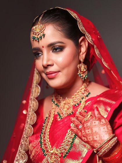 A close-up showing the details of her henna and the beautiful contrast of the green beads in her gold jewelry.