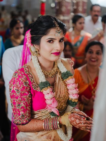 A bride during her wedding ceremony, her cream and pink saree looking soft and beautiful as she participates in the rituals.