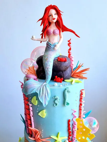 A close-up of the hand-sculpted Ariel topper, showing her holding a pearl.