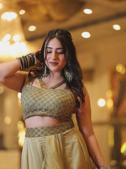 A close-up focusing on the embellished top of the olive green outfit. This highlights the craftsmanship and detail of the garment.