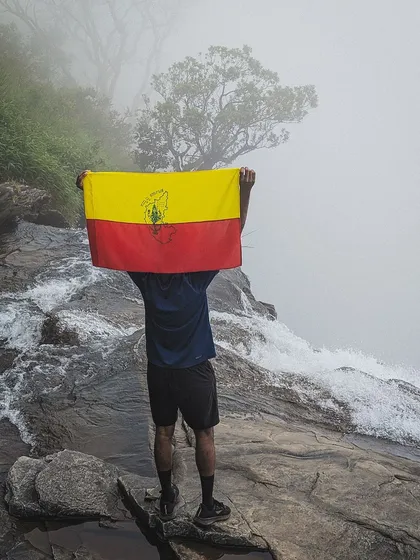 A proud trekker holding the Kannada flag at the top of Bandaje falls.