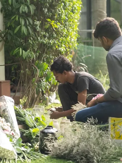 Two of my team members meticulously preparing flowers on the grass. This is where the detailed work of creating beautiful arrangements begins.