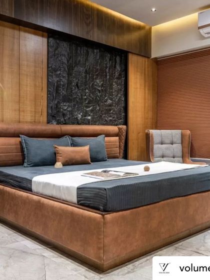 A full view of the master bedroom in the Rustic Reverie project. The combination of a rough stone feature wall, warm wood paneling, and a leather-upholstered bed creates a rich, tactile experience that is both luxurious and grounding.
