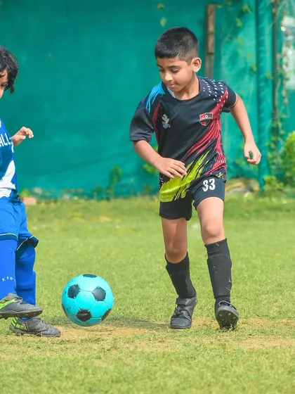 Two of our youngest athletes chase a bright blue ball, showing their love for the game.