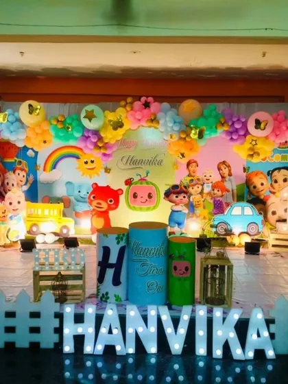A vibrant and colorful Cocomelon birthday party. The stage is filled with all the beloved characters, a rainbow, and a white picket fence, creating a cheerful and immersive setting.