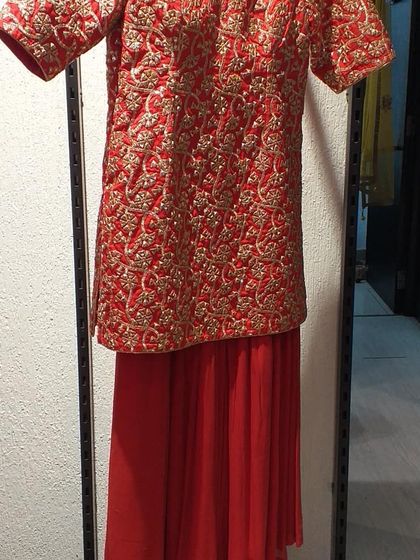 Another view of a traditional red sharara suit, showcasing the rich gold embroidery covering the entire kurta. This is a timeless piece that exudes festive elegance.
