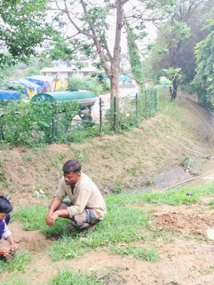 A student plants a sapling with our on-ground team member, learning the proper technique during a rainy day at the creek.