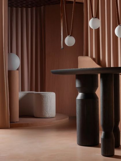 A close-up on the custom furniture and lighting. The dark wood of the table provides a grounding contrast to the soft tones of the room, while the leather-strapped pendants add a touch of rustic elegance.