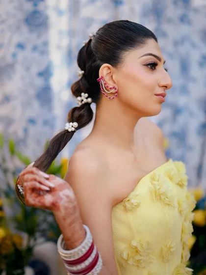 A side profile of the bride with her bubble ponytail, showing how the pearl accessories add a touch of elegance to the modern style.