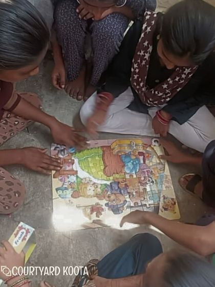 Children at the Makkala Masti camp work together to solve a floor puzzle, learning teamwork and problem solving skills.