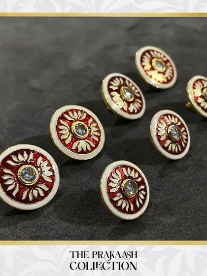 This set of round metal buttons features a striking red and white floral design with a central crystal. The detailed craftsmanship makes them an ideal choice for special occasion wear.