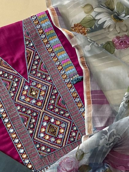 A close-up of the kurta's yoke, showcasing the geometric patterns created with thread, sequins, and mirrorwork, finished with delicate thread tassels.