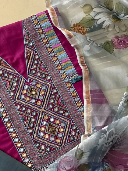 A close-up of the kurta's yoke, showcasing the geometric patterns created with thread, sequins, and mirrorwork, finished with delicate thread tassels.