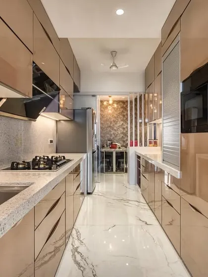 This parallel kitchen at JP Decks, Goregaon, features exquisite back-painted glass. The reflective surfaces and clean lines create a sense of spaciousness and modern luxury.