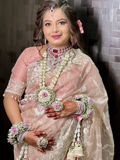 A smiling portrait of a client wearing her custom baby shower jewellery, including a necklace, bajuband, and haath phool.